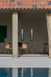 Outdoor dining area with modern furniture and terracotta-tile flooring, featuring wood frame and full-length curtains.