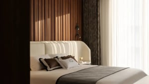Modern minimalist bedroom with a wooden headboard panel, white bedding, and illuminated wall sconce.