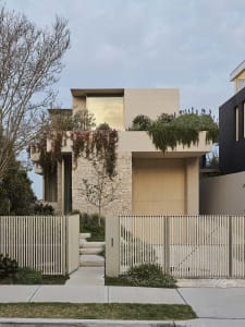 Modern house with concrete and stone exterior adorned with green plants.