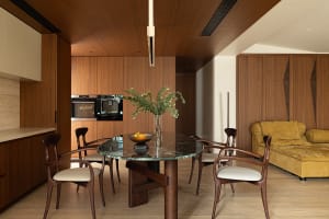 A modern residential kitchen featuring wood elements, featuring a marble dining table and a yellow couch.