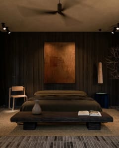 A minimalist bedroom with dark walls, wooden floors, and a low wooden bed platform.