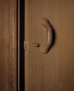 Modern minimalist closet interior featuring a wooden door handle on a textured wooden door.