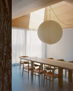 Minimalist dining room with wooden table and cloth chairs and ceiling light hanging above
