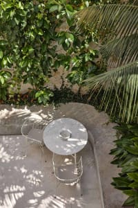 A minimalist outdoor seating area featuring a round concrete table and two matching chairs.