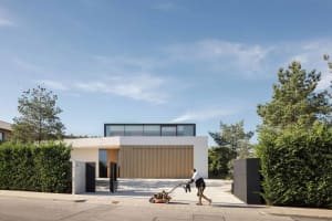 A modern house featuring concrete and glass materials with a clear front view of the exterior.