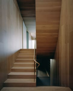 A modern interior design featuring a wooden staircase with a metal railing.