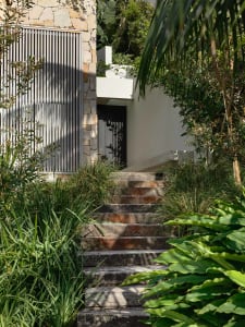 Modern residential entrance with stone steps, metal fence, and glass elements.