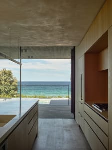 A modern residential kitchen with wooden elements and a view of the ocean.