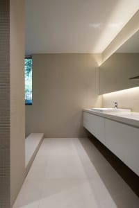 Modern minimalist bathroom with white tiles, porcelain sink, and large mirror.