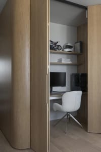 A modern home office with a wooden desk, shelves, and a white chair.