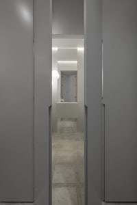 A minimalist bathroom featuring a modern concrete sink and floor, with a small mirror and light fixture.