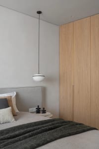 Minimalist bedroom featuring wooden features and a bed with pillows and a blanket.