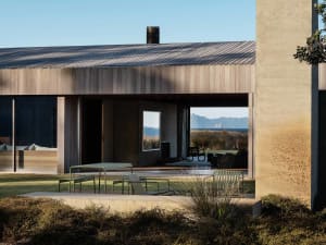 Vacation home exterior with concrete and wood materials. Modern, minimalist design with large windows and outdoor seating are