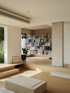 A minimalist living room featuring a black lounge chair, a plant, and a sleek entertainment unit.