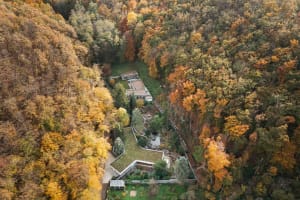 Aerial view of modern architecture nestled within an autumn forest.