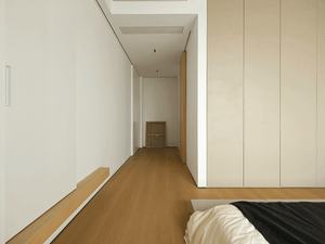 Modern minimalist bedroom with a wooden floor and bed.