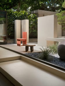 A modern minimalist garden lounge featuring geometric concrete elements and greenery.