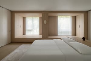 Modern minimalist bedroom with wooden walls, built-in storage, and a large bed.