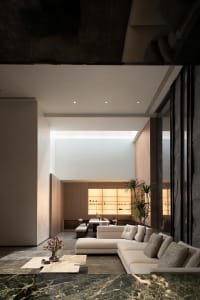 Modern minimalist living room with a concrete wall and marble accents.