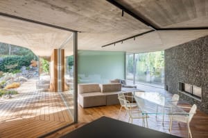 Modern living room featuring a concrete ceiling and glass walls.