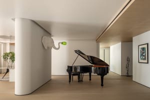 A modern living room with white walls, wooden floors, and a grand piano.