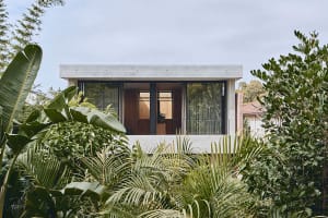 A modern residential building with a concrete exterior and large glass windows.