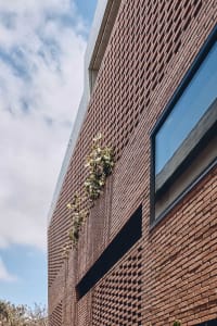 Modern building exterior with brick facade and green foliage