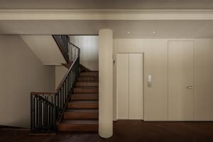 A modern industrial staircase with wooden steps and a black metal railing.