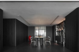 A modern minimalist dining room with black wood furniture and a round table surrounded by chairs.