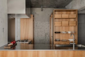 Modern minimalist residential kitchen with concrete hexagonal patterned backsplash, wooden cabinetry, and stainless steel app