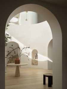 Modern minimalist interior space with light-colored walls, arched doorways, and natural light.