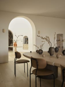 A minimalist dining room with a wooden table, chairs, and decorative vases