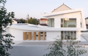 Modern house exterior with white painted walls, large glass windows, and wooden accents.