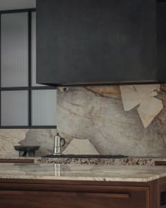 Modern kitchen featuring a sleek marble backsplash and countertop, with a stainless steel espresso maker on the countertop.