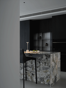 Modern kitchen with marble countertop and black cabinets.