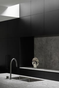 Modern minimalist kitchen featuring concrete countertops and marble backsplash