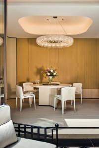 A modern dining room with a white marble table, white chairs, and a flower arrangement on the table.