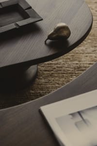A bronze pear-shaped decorative object placed on a wooden curved table, featuring textured surface and modern design aestheti