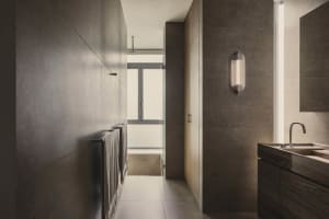 Modern bathroom with concrete walls and floor, featuring a sleek, minimalist design with a light fixture, window, and sink.