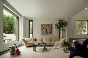 A modern minimalist living room with a white sectional sofa, abstract art, and large windows.