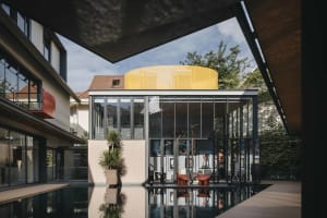 A modernist living space extension featuring glass walls and a pool.