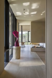 A modern residential interior with concrete flooring, large windows, and a fireplace.