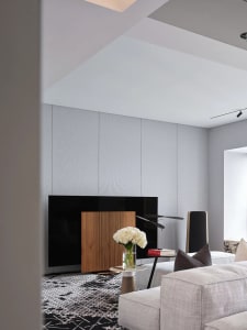 A modern living room featuring minimalist furniture, a wooden cabinet, and a gray sofa.