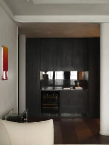 A modern minimalist kitchen with dark wooden cabinets, marble countertops, and metallic accents.