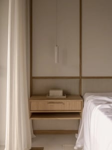 Minimalist bedroom with a floating nightstand, wooden elements, and a sleek pendant lamp.