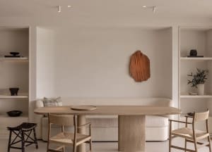 A minimalist living room with natural wood and concrete textures, featuring a sleek dining table and contemporary furniture.