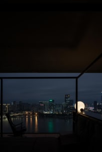 Interior night view showing a cityscape through a glass window frame.
