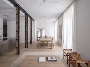 Modern minimalist living room with white walls, wooden furniture, and steel accents.
