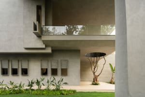 A minimalist house exterior featuring a concrete structure and green landscaping.