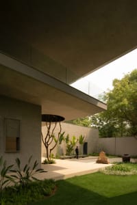 A minimalist modern garden with concrete structures and greenery.